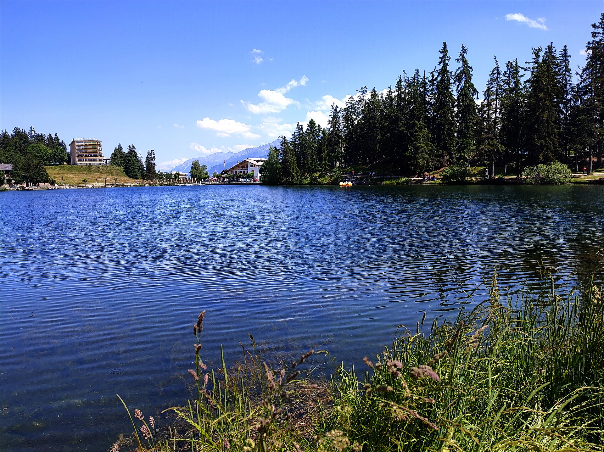Lac de montagne de Crans-Montana en été, forêt et sommets
