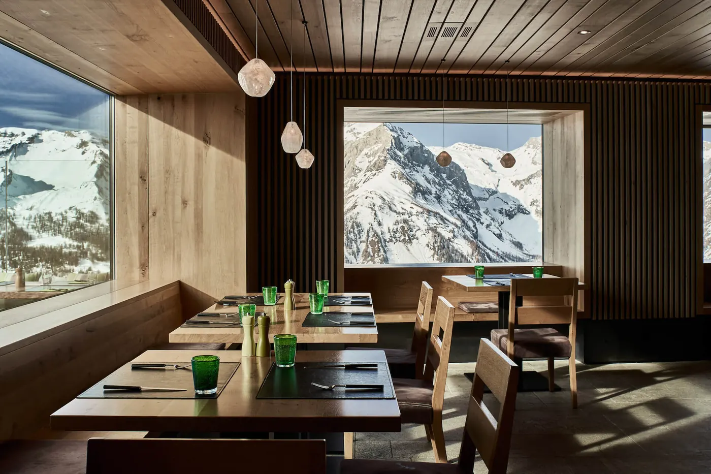 餐厅用餐区,浅色木饰,餐桌临窗而设,窗外是白雪覆盖的山峰