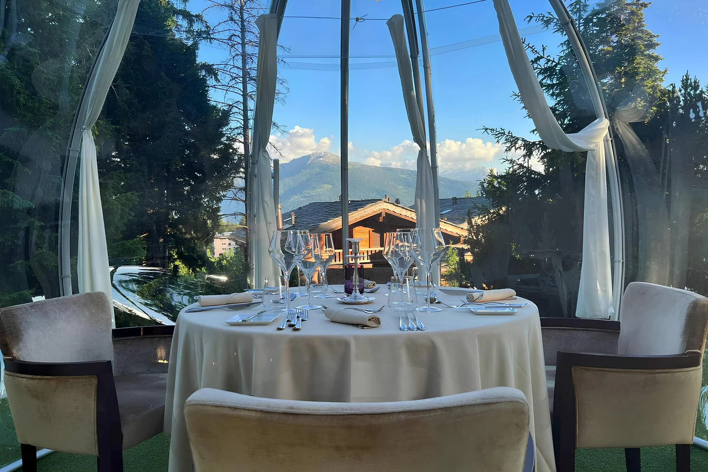 Igloo Royal 内布置好的餐桌,透明圆顶外是木屋与群山